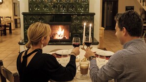 A couple seated at a table with a fireplace in the background. - Pensiunea Sibiel (Sibiel)