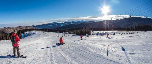 Pista de esquí con esquiadores y snowboarders, un telesilla y cielo despejado.