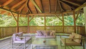 A covered outdoor seating area with wooden beams, a cushioned sofa, and a coffee table. - Pensiunea Sibiel (Sibiel)