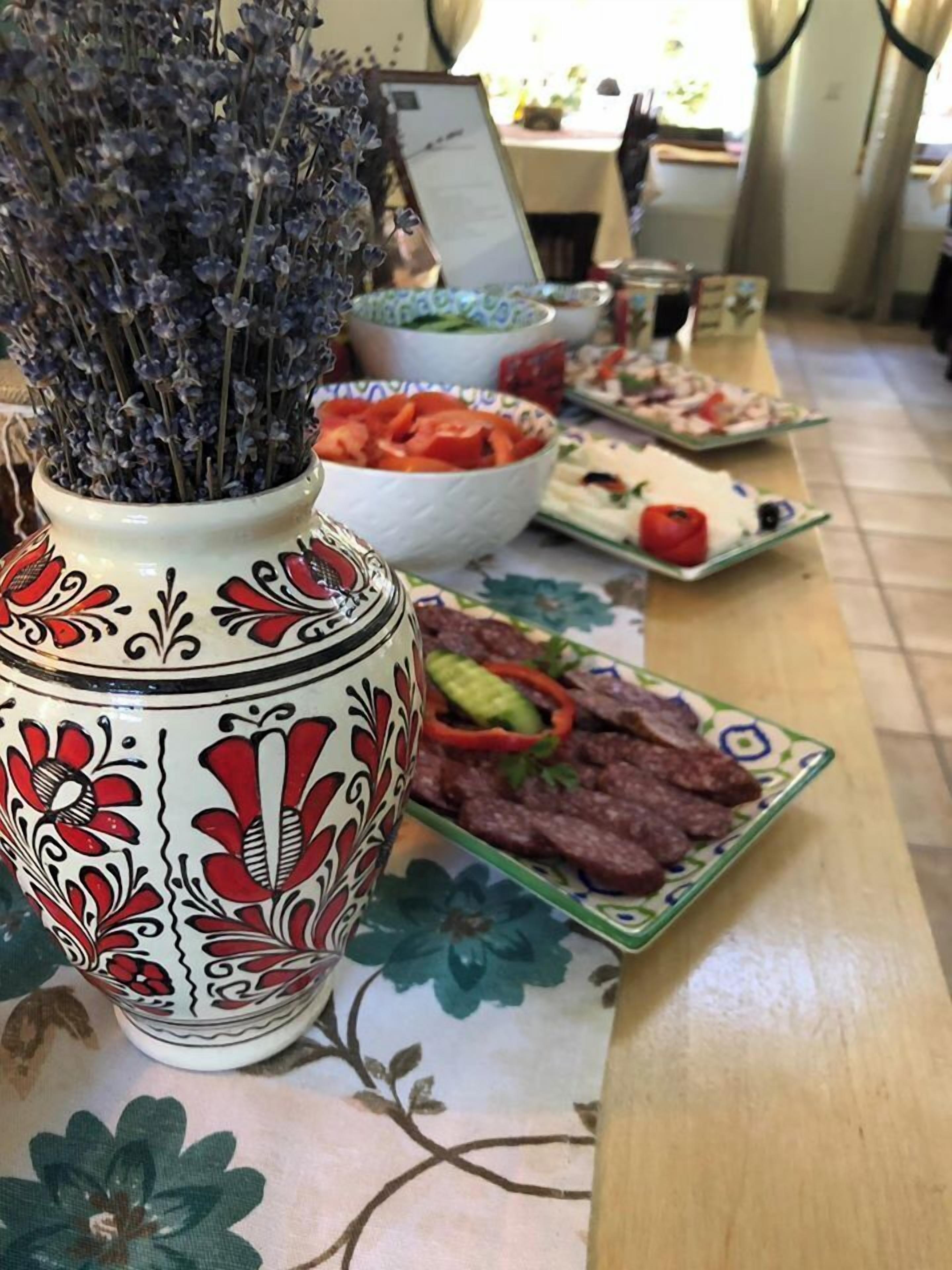 A table with a decorative vase, a bowl of sliced vegetables, and plates of food.