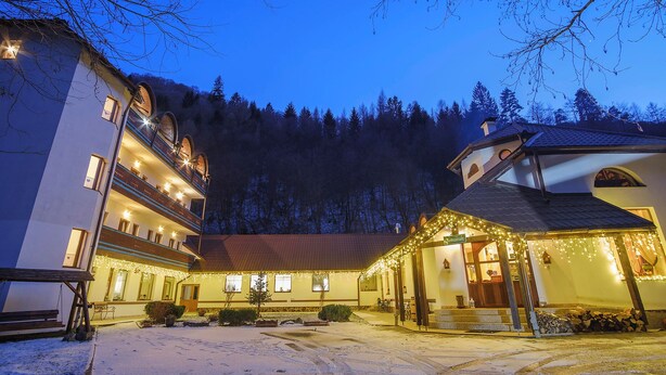 A hotel with multiple floors, a covered outdoor area with string lights, and a snowy courtyard. - Pensiunea Sibiel (Sibiel)
