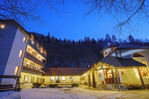 Un hotel con varios pisos, un espacio exterior cubierto con guirnaldas de luces y un patio nevado.