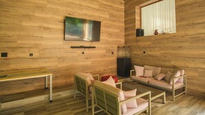 A modern living room with wooden walls, a flat-screen TV, a sofa, a coffee table, and a bench. - Pensiunea Sibiel (Sibiel)
