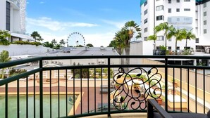 A balcony with a view of a Ferris wheel, palm trees, and modern buildings.