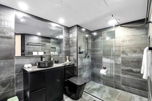 Un bagno moderno con cabina doccia in vetro, un mobile lavabo nero e uno specchio grande.