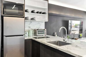 Una cucina moderna con forno a microonde integrato, un tostapane e un lavandino.