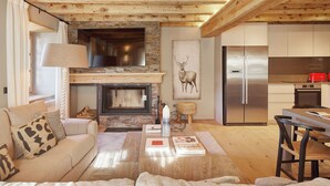 A cozy living room with a fireplace, a sofa, and a dining area with a table and chairs. - Pleta Baqueira Luxe 10 by FeelFree Rentals (Baqueira)