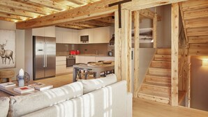 A modern kitchen with wooden beams, stainless steel appliances, and a dining area with a sofa and books. - Pleta Baqueira Luxe 10 by FeelFree Rentals (Baqueira)