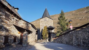 A narrow cobblestone street flanked by stone buildings with a church steeple in the background. - Pleta Baqueira Luxe 10 by FeelFree Rentals (Baqueira)