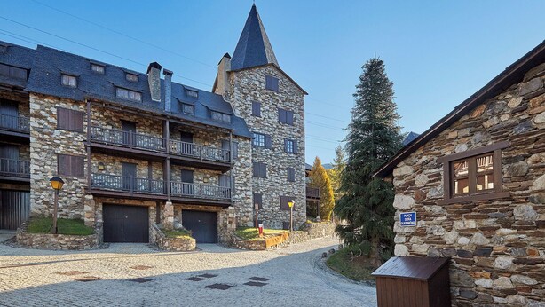A stone building with a tower, a cobblestone street, and a sign indicating a place for rest. - Pleta Baqueira Luxe 10 by FeelFree Rentals (Baqueira)