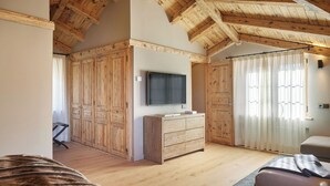 A room with wooden ceiling beams, a large wardrobe, a flat-screen TV, and a window with curtains. - Pleta Baqueira Luxe 10 by FeelFree Rentals (Baqueira)