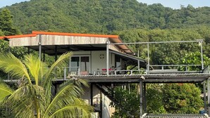A wooden structure with a red roof, possibly a guesthouse or small building, with a view of a lush green mountain in the background. - Baan Plai Laem Resort (Ko Phaluai)