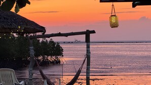 A beach scene with a hammock, chairs, and a hanging lantern. - Baan Plai Laem Resort (Ko Phaluai)