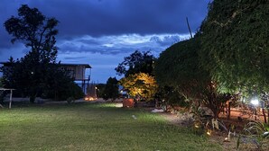 A grassy outdoor area with a building structure, trees, and a clear sky. - Baan Plai Laem Resort (Ko Phaluai)