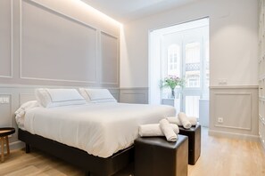 A modern bedroom with a large bed, a bedside table, and a window with a view of buildings. - "La Bella Easo" new, ac, design, near La Concha (Donostia-San Sebastian)