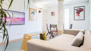 A modern room with a sofa, a small table, and a chair. There are framed artworks on the walls and a television on the left. - "The Palms" new, ac, terrace, calm near Old Town (Donostia-San Sebastian)
