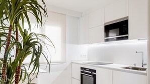 A modern kitchen with white cabinetry, a built-in oven, a microwave, and a sink. - "The Palms" new, ac, terrace, calm near Old Town (Donostia-San Sebastian)