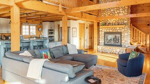 A spacious living area with a large sectional sofa, a cozy fireplace, and a stone accent wall.