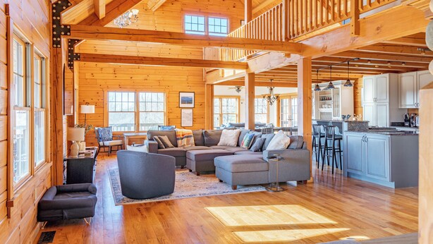 A spacious log cabin interior with a large living area, a kitchen, and a dining area.