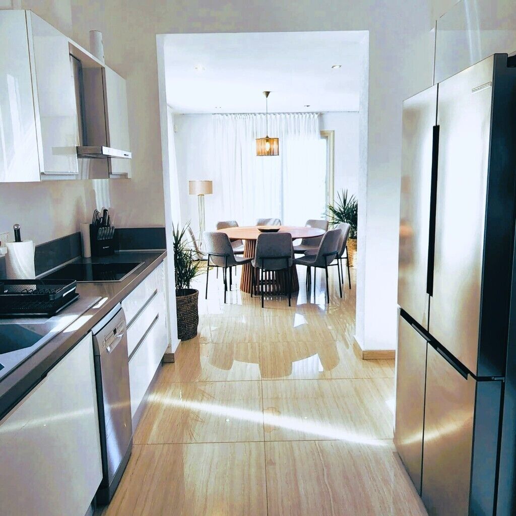 A modern kitchen with a dining area, stainless steel appliances, and a wooden floor.