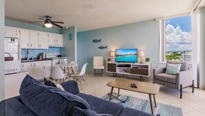 Ett modernt vardagsrum med en soffa, ett soffbord, en tv och en matplats med stolar och ett bord.