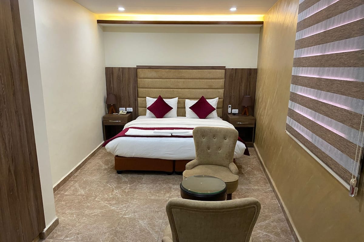 A hotel room with a large bed, two bedside tables, a chair, and a small table.