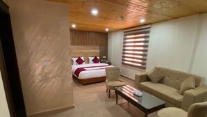 A hotel room with a bed, a sofa, a coffee table, and a chair. - Sunset hotel (Wadi Musa)