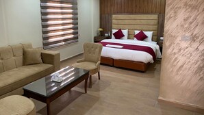 A modern hotel room with a wooden ceiling, a large bed with red and white bedding, a beige sofa, a glass coffee table, and a wooden nightstand. - Sunset hotel (Wadi Musa)