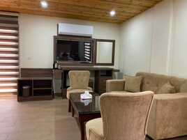 Una sala de estar moderna con un sofá, una mesa de centro de vidrio y un televisor montado sobre un mueble de madera.