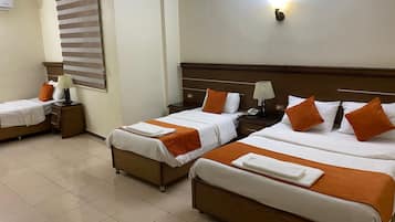 Une chambre d’hôtel avec deux lits, une table de chevet avec une lampe, un luminaire fixé au mur et une fenêtre avec des stores.
