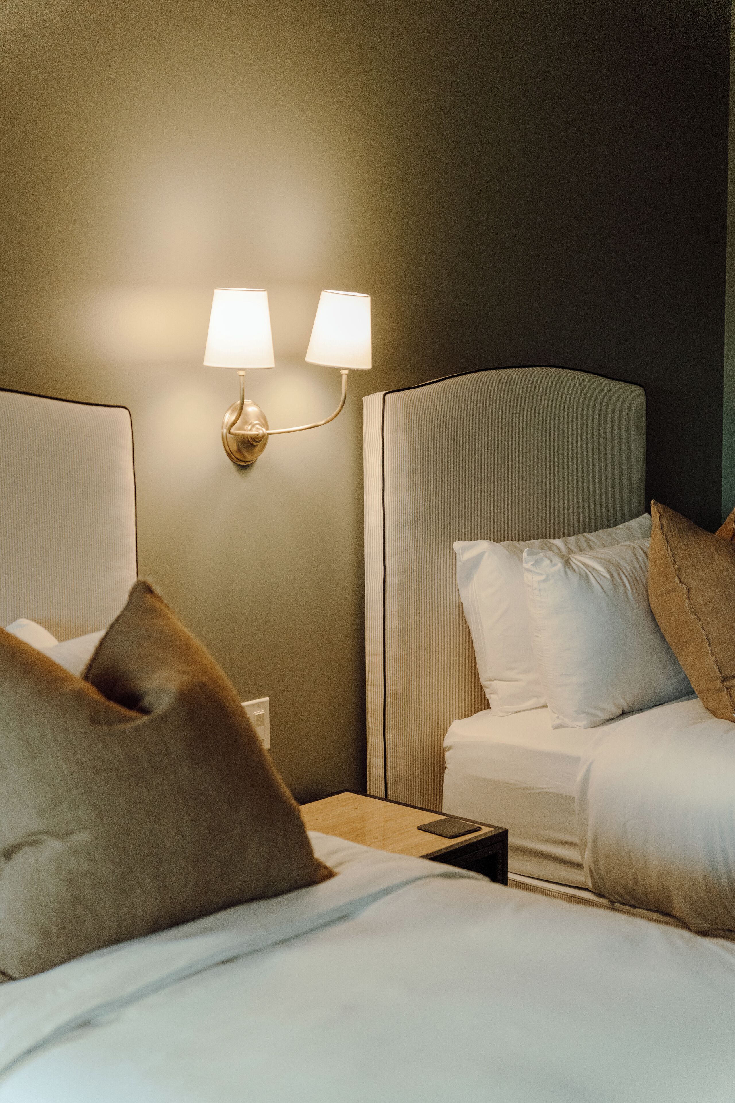 Une chambre d’hôtel comprenant un lit, deux lampes de chevet, une table de chevet et un luminaire fixé au mur.