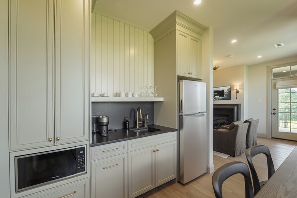 Una cocina moderna con armarios blancos, un refrigerador de acero inoxidable y un microondas.