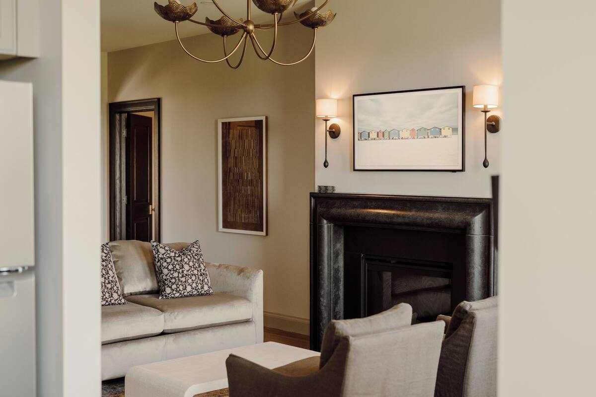 A living room with a fireplace, a sofa, a coffee table, and wall-mounted artwork.