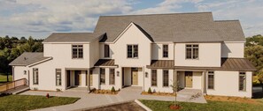 A two-story house with a symmetrical facade, a covered front porch, and a landscaped front yard. - The Penrose Suites (Saint Marys)