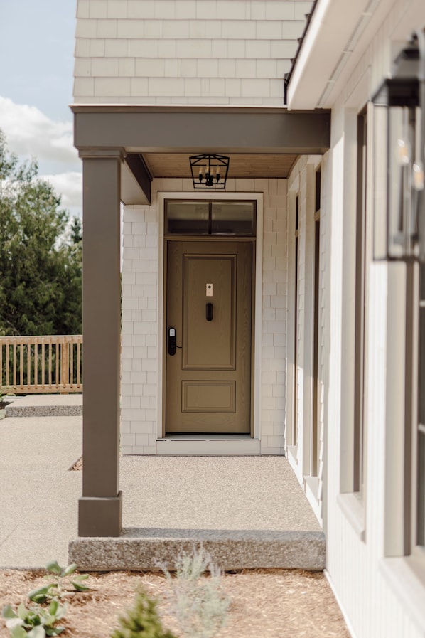 A building with a beige door, white brickwork, and a wooden deck. - The Penrose Suites (Saint Marys)