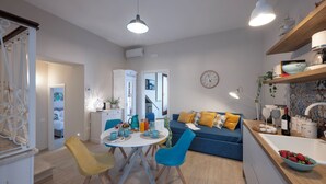 Une cuisine moderne avec un coin repas, un canapé bleu et un comptoir de cuisine sur lequel sont disposés divers objets.