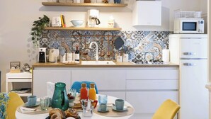 Une cuisine moderne avec un coin repas, comprenant une table ronde avec des chaises, divers appareils de cuisine et un crédence décorative.