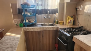 Une cuisine de taille réduite, équipée d’un évier, d’une cuisinière et de meubles de rangement en bois.