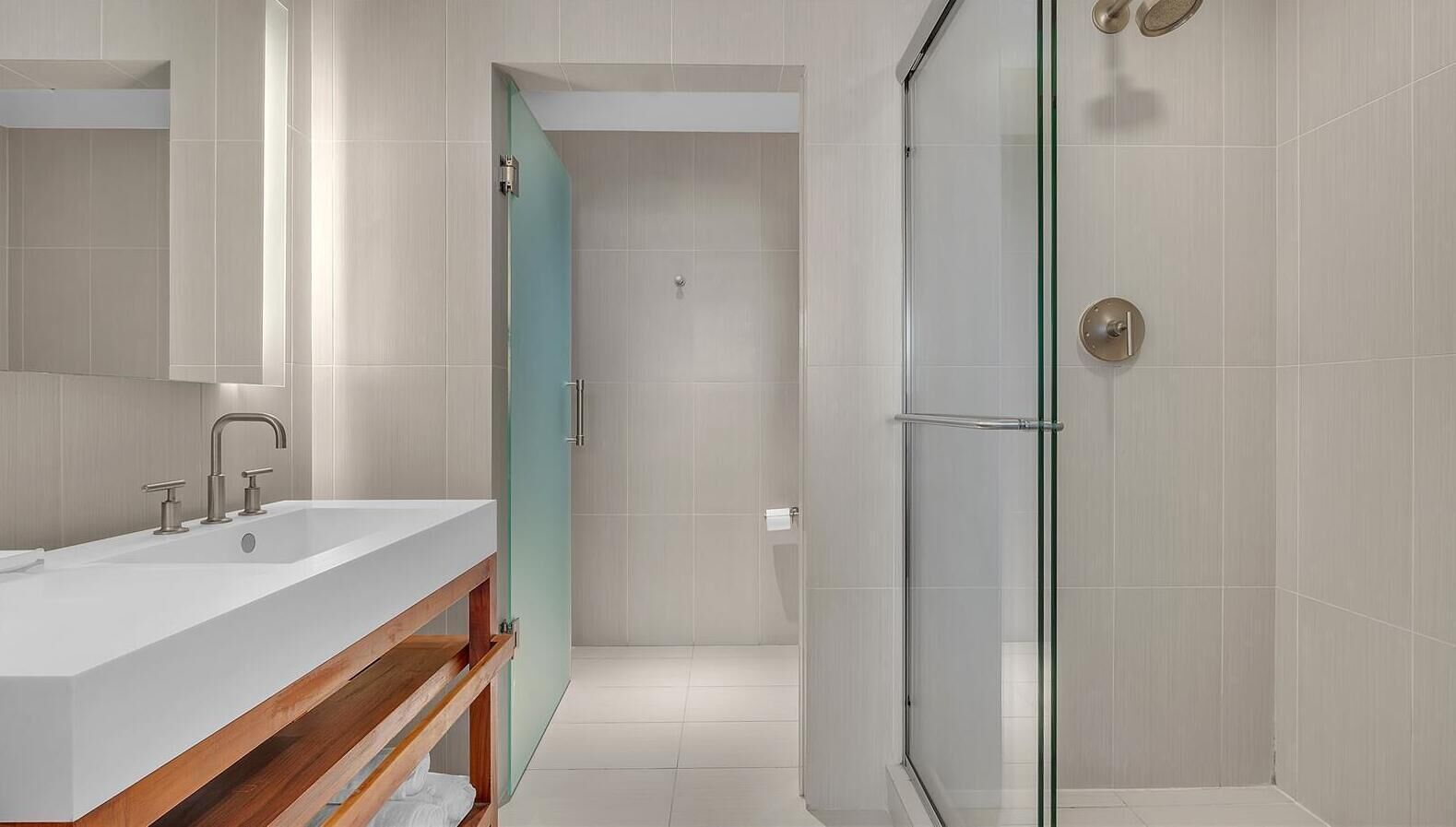 A modern bathroom with a large sink, a glass shower enclosure, and a wooden vanity.
