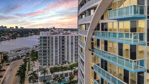 A high-rise hotel with multiple balconies, a swimming pool, and a view of a river and city skyline. - Lux Two BR Suite at W Fort Lauderdale (Fort Lauderdale)