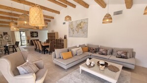 A modern living room with a sectional sofa, a round coffee table, and a dining area with a wooden table and chairs. - Villa Antassi  14 minute stroll to restaurants, wellness facilities, the beach (Grimaud)