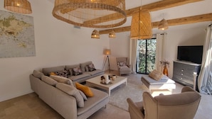 A living room with a sofa, armchairs, a coffee table, and a TV. There are wicker lamps and a map on the wall. - Villa Antassi  14 minute stroll to restaurants, wellness facilities, the beach (Grimaud)