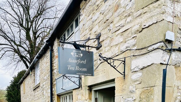 Ein Steinhaus mit einem Schild für 'Alseford Tea Room' und einer Kreidetafel-Speisekarte vor der Tür.