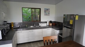 A modern kitchen with a stainless steel refrigerator, a sink, and a window with a view of greenery. - Fully equipped 2-bedroom apartment close to mountains and beach with great WiFi (Playa Hermosa)