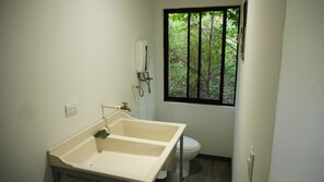 Enjoy a refreshing bathroom with a sink, toilet, and window offering a view of the surrounding greenery.