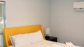 A neatly made bed with white linens and a yellow headboard in a room with light blue walls and a wooden floor. - 1 Bedroom Apartment in North Charleston (North Charleston)