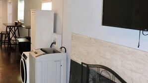 A laundry area with a washing machine and dryer, a fireplace, and a television mounted on the wall. - 1 Bedroom Apartment in North Charleston (North Charleston)