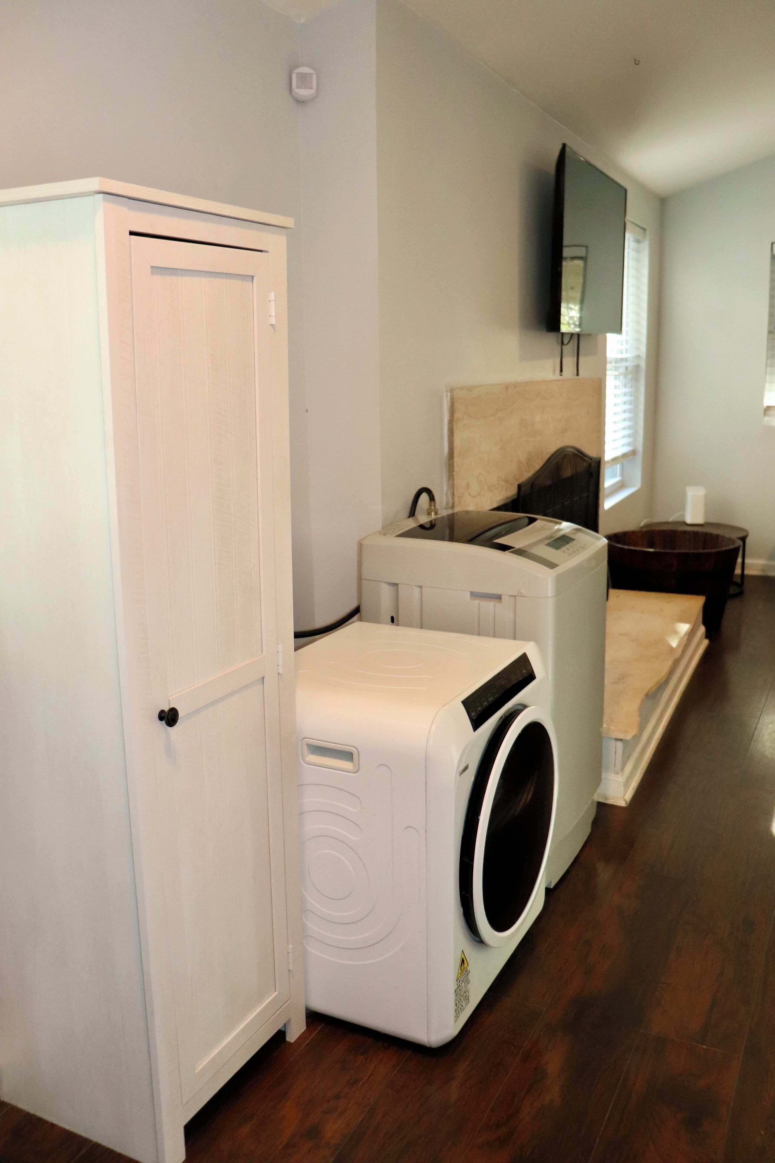 A laundry room with a washer and dryer, a cabinet, and a mirror on the wall.