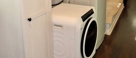 A laundry room with a washer and dryer, a cabinet, and a mirror on the wall.
