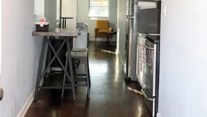 A modern kitchen with stainless steel appliances, a wooden table, and a yellow chair. - 1 Bedroom Apartment in North Charleston (North Charleston)